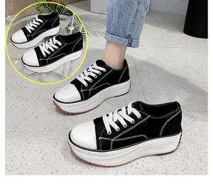 Close-up detail of black canvas platform sneakers with thick white soles on feet