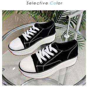 Detail view of black low-top thick-sole canvas sneakers with white laces on a table