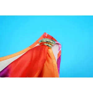 Detailed macro view of elegant golden metal ring buckle on floral one-shoulder jumpsuit