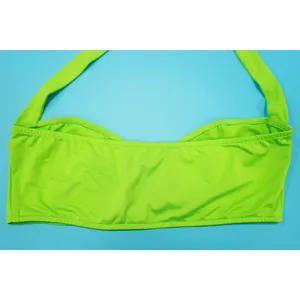 Detailed macro view of vibrant neon green halter bikini top with smooth fabric finish