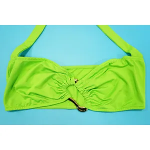 Detailed macro shot of a lime green halter bikini top featuring a shiny gold metal buckle