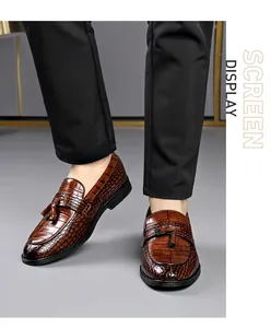 Macro view of men's brown crocodile embossed leather loafers featuring elegant tassel detail
