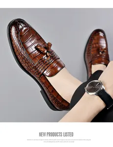 Detail of brown crocodile-patterned leather loafers with tassels.