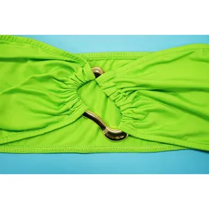 Detail shot of neon green swimwear fabric with a wavy gold metal decorative link