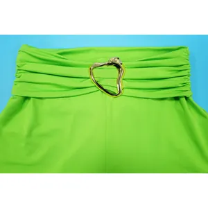 Close-up detail of lime green garment featuring a gold irregular heart buckle and ruching.