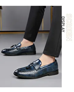 Close-up of navy blue crocodile-patterned loafers with tassels on a male model.