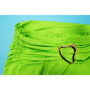 Close-up of neon green halter set waist with gold heart-shaped decorative buckle detail.