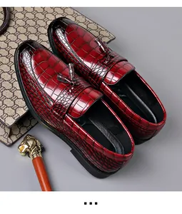 Macro view of the embossed crocodile skin texture and tassel detail on red men's loafers.