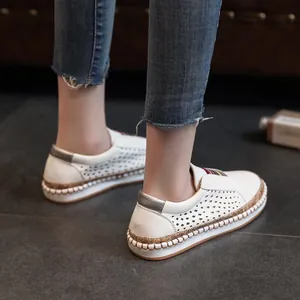 Close-up van witte lasergesneden loafers met een kleurrijke streep gedragen door een model.