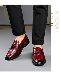 Close-up of burgundy crocodile pattern loafers with tassel detail and sleek finish.