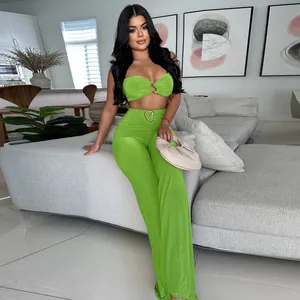 Model wearing neon green tube top and wide-leg pants outfit set in a modern living room