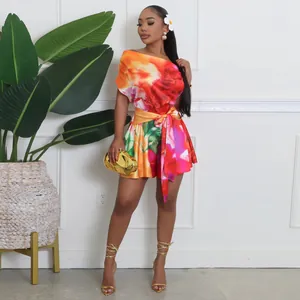 Detail of vibrant floral print romper with asymmetrical one-shoulder and waist tie