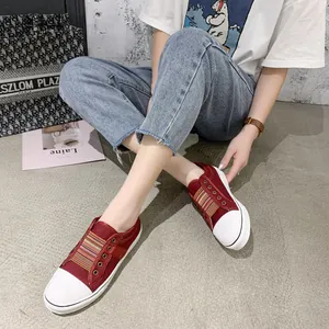 Lifestyle detail of vintage red canvas sneakers with striped elastic bands and white toe