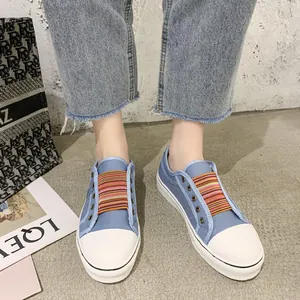 Close-up of blue canvas sneakers with colorful elastic bands and thick white soles