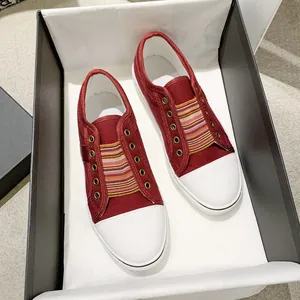 Top view of red casual canvas shoes with colorful striped elastic bands in a shoe box