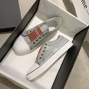 Detail view of grey canvas sneakers featuring colorful elastic bands inside a shoebox
