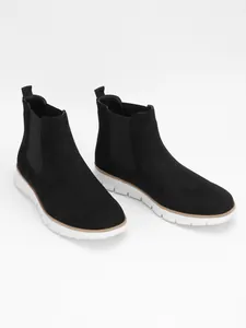 Detail view of men's casual black Chelsea boots featuring lightweight white soles