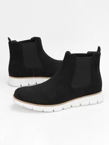 Close-up detail of men's black suede Chelsea boots with lightweight white sole