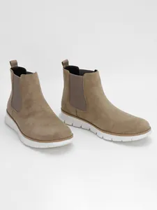 Close-up detail of men's khaki suede Chelsea boots featuring white flexible outsoles.
