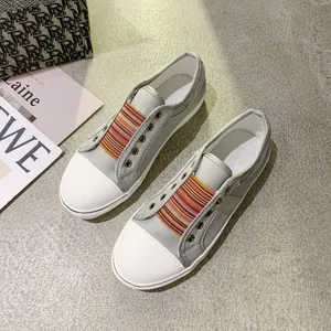 Detailed view of grey canvas sneakers with colorful elastic bands and thick white soles