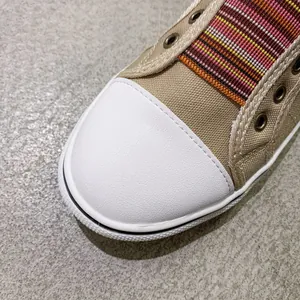 Close-up of canvas shoe toe cap with colorful striped elastic band detail.