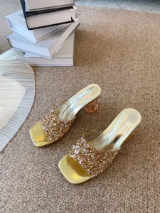 Mules dorati a punta quadrata con cinturini in strass e tacchi trasparenti larghi ed eleganti.