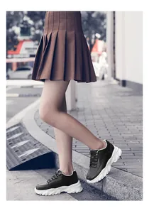 Side view of black chunky platform sneakers with 8cm thick white sole on a street