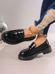 Detail of black chunky platform loafers in British style worn with ripped jeans