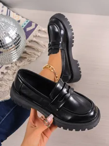 Close-up shot of black chunky platform loafers featuring a retro British design