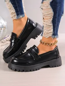 Close-up of stylish black platform loafers featuring thick chunky soles and British style.