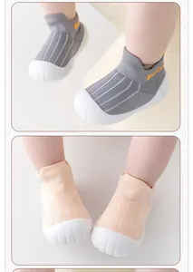 Detail of breathable baby walker shoes with non-slip soft soles in grey and peach colors.