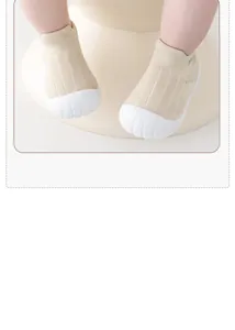 Close-up view of beige knit baby toddler shoes featuring protective white rubber toe caps