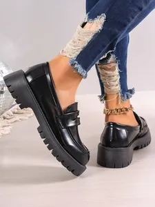 Close-up of black platform loafers with thick lug soles and distressed denim styling