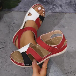 Gros plan de sandales compensées color-block avec bride velcro et bout ouvert.
