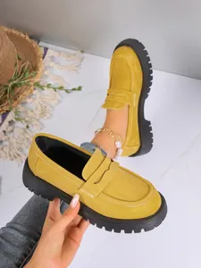 Close-up detail of yellow chunky platform loafers featuring white stitching accents