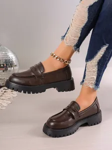 Detailed shot of dark brown chunky platform loafers worn with distressed denim jeans