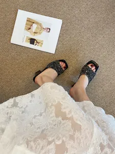 Eleganti sabot neri con paillettes e tacco largo abbinati a un abito in pizzo bianco
