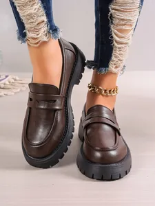 Close-up of vintage dark brown chunky loafers with thick soles on model's feet.