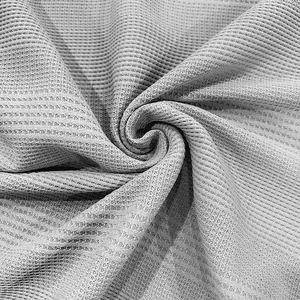 Detalle macro que muestra el tejido de punto waffle gris transpirable de un polo