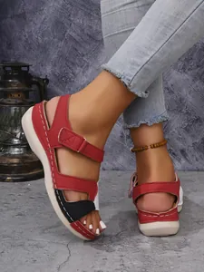 Gros plan de sandales compensées bicolores rouge et noir avec brides auto-agrippantes