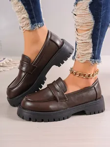 Macro view of women's dark brown loafers featuring thick chunky soles and retro British style