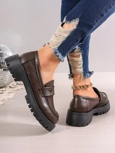 Close-up of dark brown platform loafers with thick lug soles in a trendy casual setting.