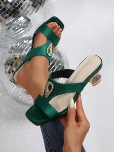 Close-up of green satin square toe heeled sandals with teardrop rhinestone detail