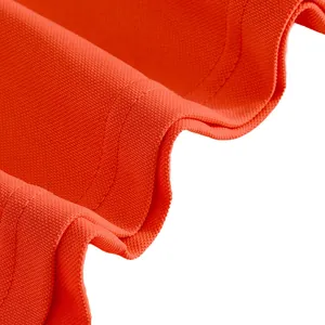 Close-up macro view of orange quick-dry mesh fabric and stitching detail for men's polo shirt.