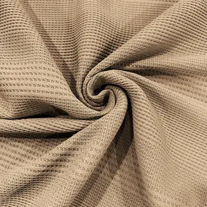 Vista detallada de la textura del tejido de punto de gofre beige para polo de hombre.