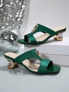 Close-up of green satin square-toe slide sandals with rhinestone and clear block heel.