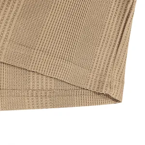 Primer plano del tejido de punto gofrado caqui y la costura del dobladillo de un polo para hombre