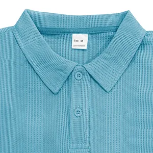 Primer plano del cuello de un polo azul de punto gofrado con botón y etiqueta de talla M