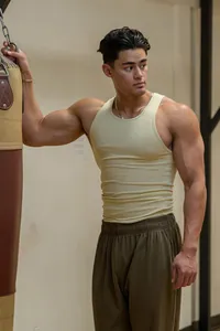 Gespierde man in een lichtgeel geribbeld fitness-tanktop in een sportschoolomgeving