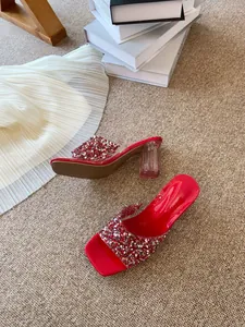 Dettaglio di eleganti sabot rossi con strass scintillanti e tacco in cristallo trasparente